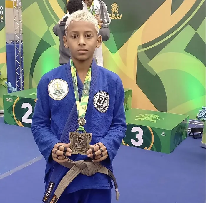 Ícaro de Araújo de quimono azul, segurando a medalha do Brasileiro de Jiu-Jitsu Crianças